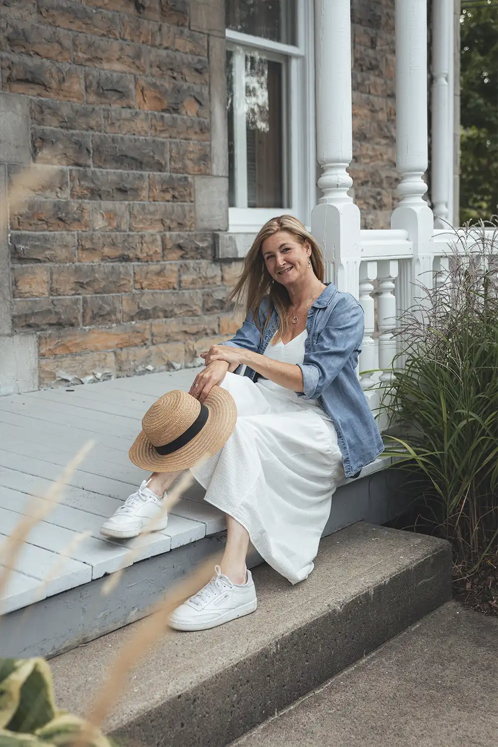 Portrait of a woman sitting on a porch with her hat
