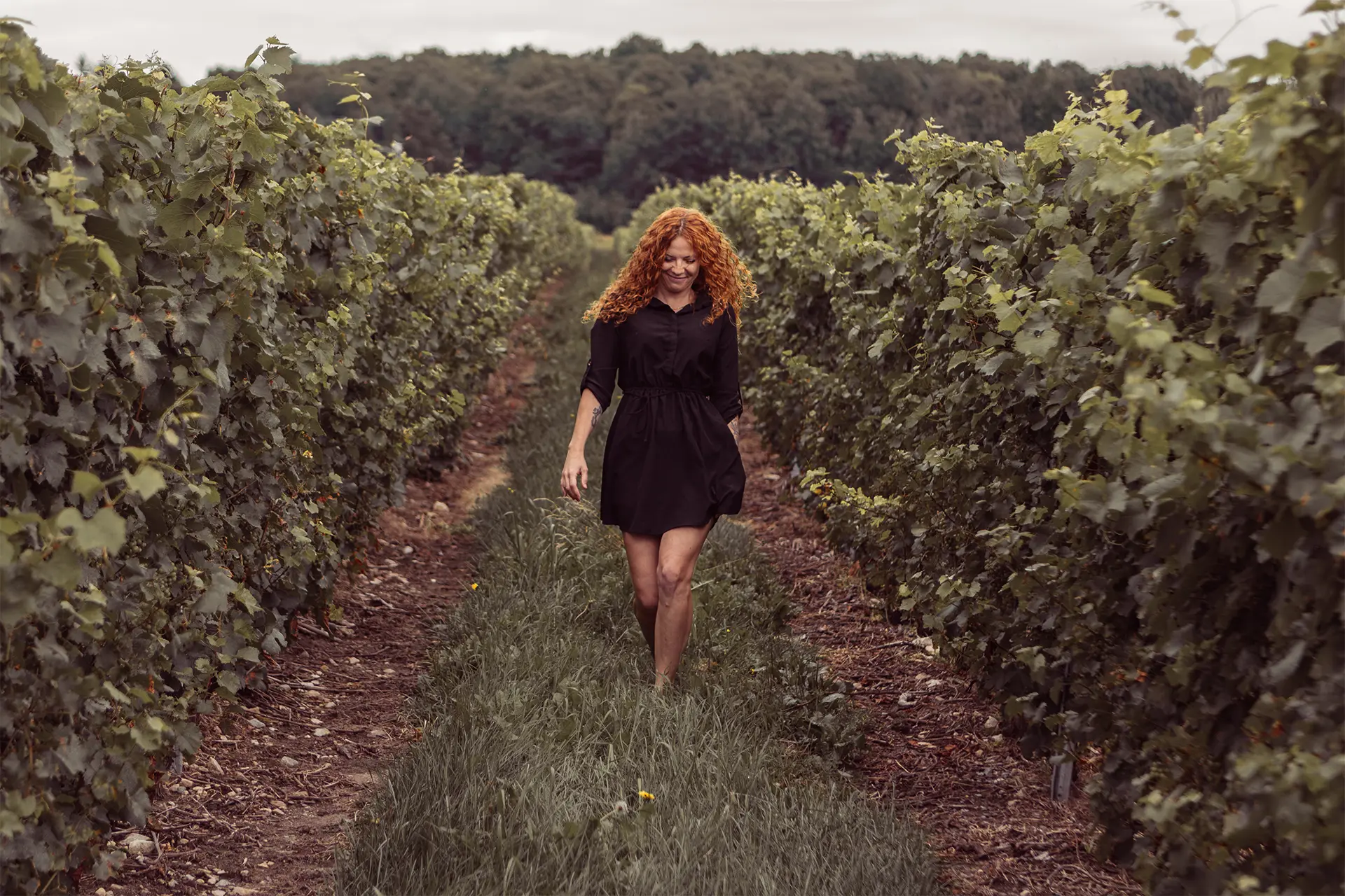 Portrait of a red headed woman walking down a vineyard